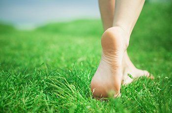Healthy bare foot stepping across green grass